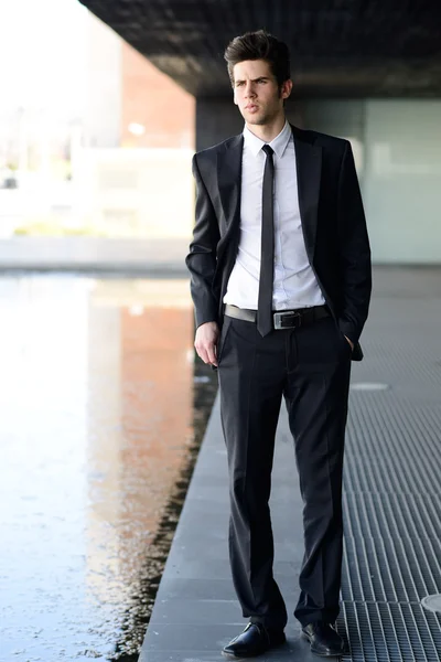 Attractive young businessman in urban background — Stock Photo, Image