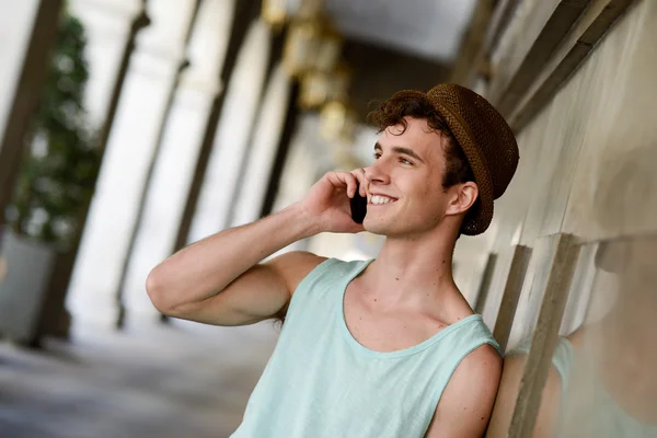 Attractive young man wearing hat talking on the mobile phone — Stock Photo, Image