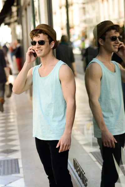 Attractive young man wearing hat talking on the mobile phone — Stock Photo, Image