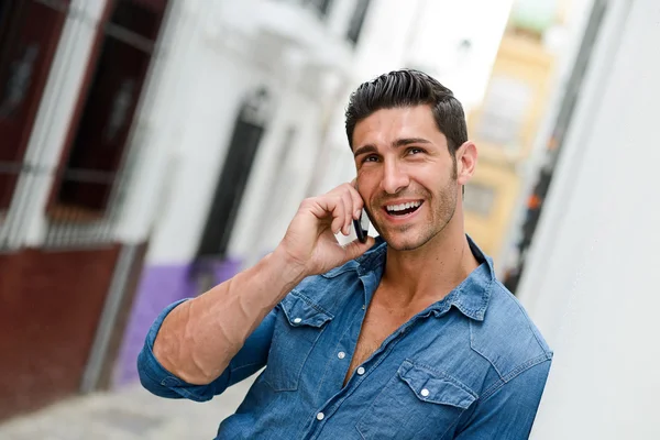 Hombre guapo en el fondo urbano hablando por teléfono —  Fotos de Stock