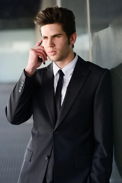 Attraktiver junger Geschäftsmann am Telefon in einem Bürogebäude — Stockfoto