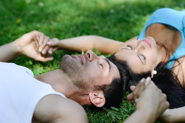 Yeşil çimenlerin üzerinde döşeme gülümseyen mutlu çift — Stok fotoğraf