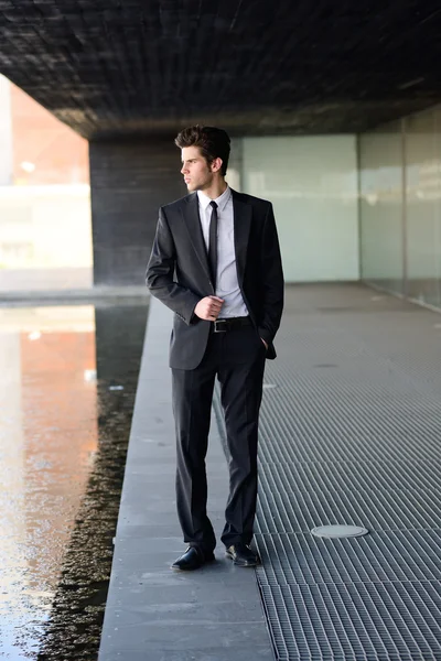 Attractive young businessman in urban background — Stock Photo, Image