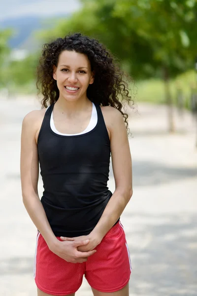 Giovane donna allegra sorridente in abbigliamento sportivo in background urbano — Foto Stock