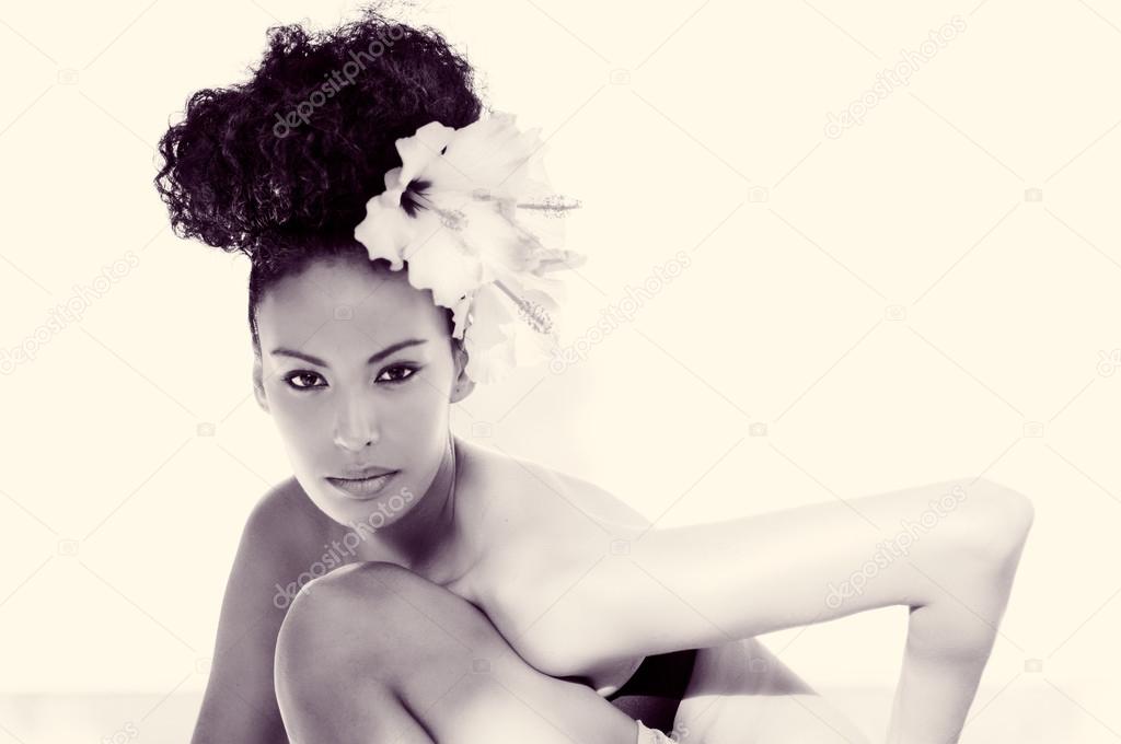 Black woman, model of fashion, with big flowers in her hair 