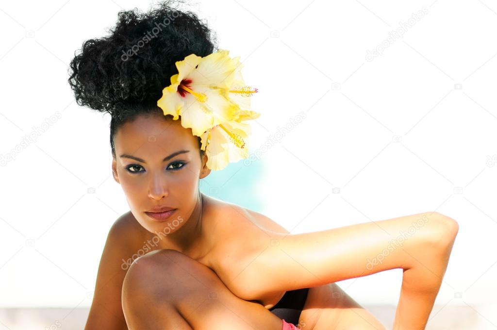 Black woman, model of fashion, with big flowers in her hair 