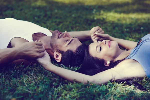 Happy smiling couple laying on green grass — Stock Photo, Image