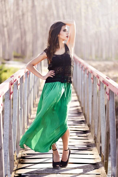 Vrouw die lange jurk draagt in een landelijke brug — Stockfoto