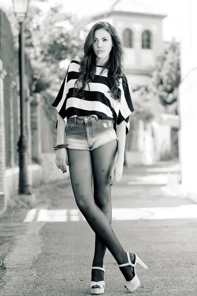 Mujer atractiva con pantalones cortos de mezclilla en fondos urbanos — Foto de Stock