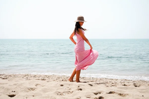Beautiful woman with long pink dress and sun hat on a tropical b — Stock Photo, Image