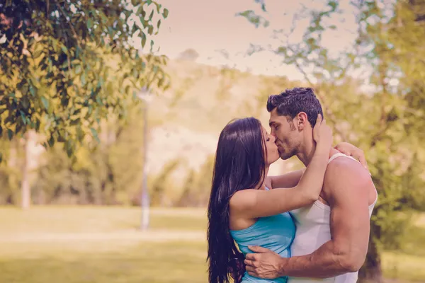 Молодая пара целуется в красивом парке Стоковая Картинка