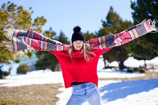 Mujer rubia joven feliz agitando su bufanda en el viento en un bosque en las montañas nevadas. — Foto de Stock