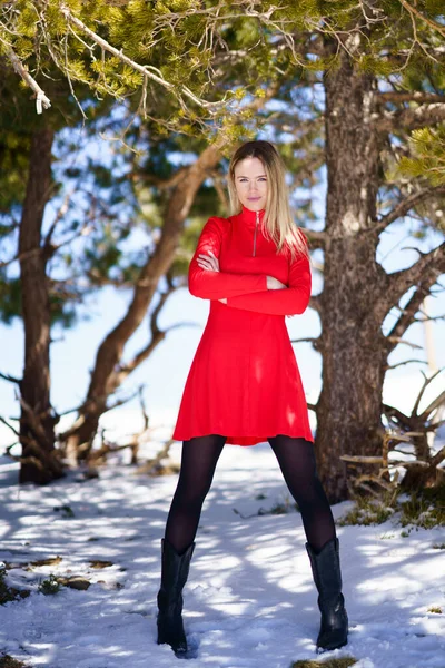 Szőke nő visel piros ruhát és fekete harisnya a havas hegyekben télen. — Stock Fotó