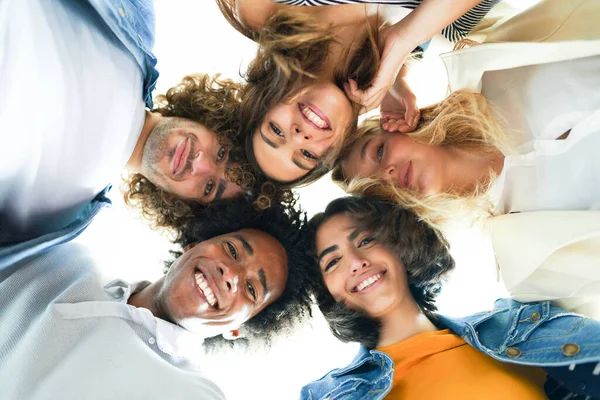 Multi-ethnic group of friends with their heads together in a circle. — Stock Photo, Image