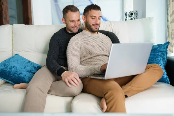 Homosexuella par konsulterar sina resplaner tillsammans med en bärbar dator. — Stockfoto