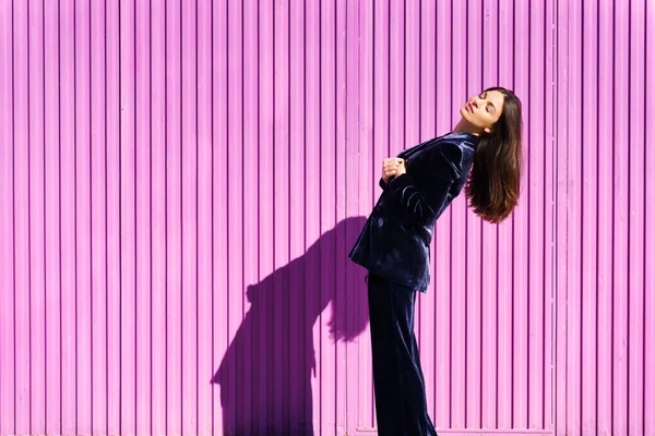 Woman wearing blue suit posing near pink shutter. — Stock Photo, Image