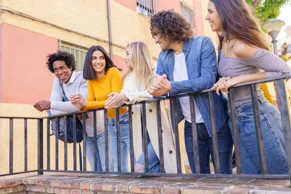 Eine multiethnische Gruppe von Freunden versammelte sich auf der Straße, angelehnt an ein Geländer. — Stockfoto