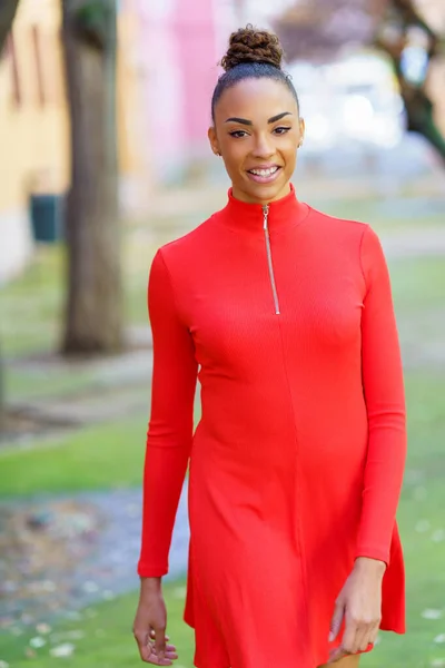 Femme noire souriante en robe rouge marchant dans la rue — Photo