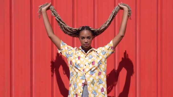 Chica africana peinada con trenzas de colores dejándolos caer. Peinado típico africano. — Vídeo de stock