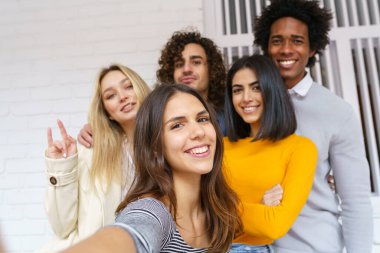 Çok ırklı bir grup arkadaş dışarıda eğlenirken selfie çekiyorlar..