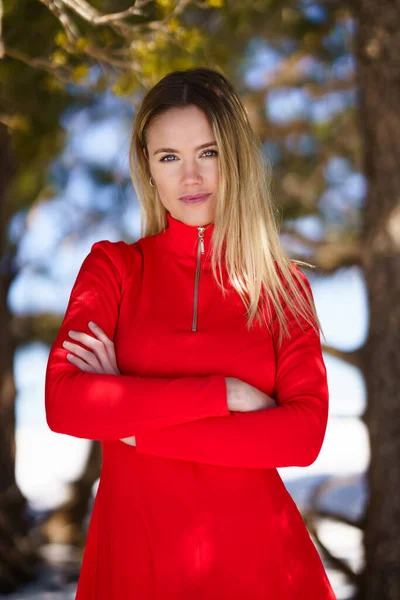 Jonge blonde vrouw draagt een rode jurk in de besneeuwde bergen in de winter. — Stockfoto