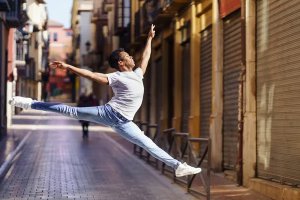 Junger schwarzer Mann macht einen akrobatischen Sprung mitten auf der Straße. — Stockfoto