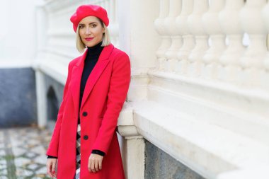 Kırmızı kışlık giysiler giyen orta yaşlı güzel bir kadın kameraya bakıyor..