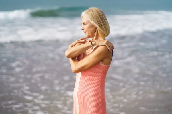 Volwassen vrouw aan de kust van een strand. Oudere vrouw geniet van haar pensioen op een terugtocht aan zee. — Stockfoto