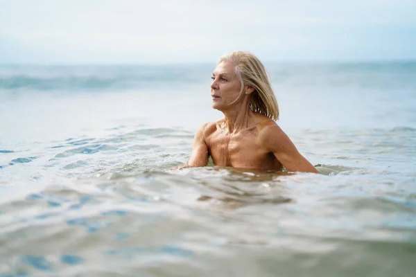 Oudere vrouw in goede vorm baden in de zee. — Stockfoto