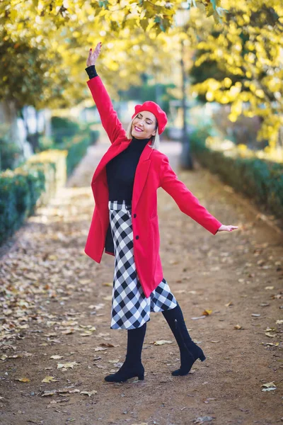 Šťastná žena v červeném zimním oblečení otevírá náruč se zavřenýma očima venku. — Stock fotografie