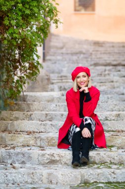 Kırmızı kışlık kıyafetler giyen bir kadın, Granada 'da Albaisin' de merdivenlerde oturuyor..