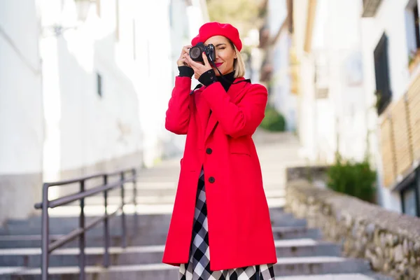 Mujer tomando una fotografía con una cámara réflex vistiendo ropa roja de invierno. — Foto de Stock