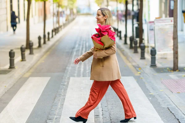 Mujer que lleva una poinsettia que acaba de comprar en una tienda de plantas. — Foto de Stock
