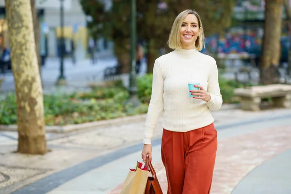 Vrouw winkelen en draagtassen en een kopje koffie in een meeneembeker. — Stockfoto