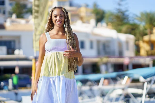 Blandad kvinna går längs en hamn klädd i en fin sommarklänning. — Stockfoto