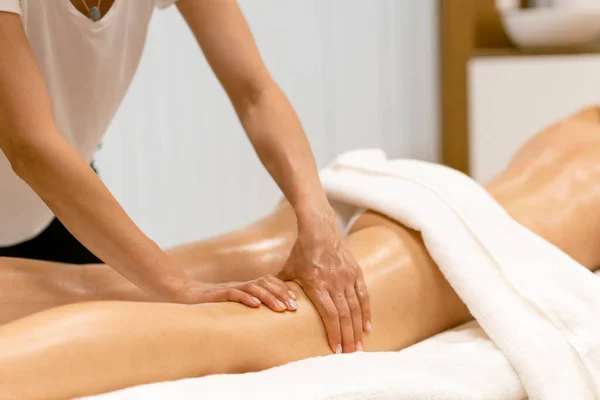 Salão de beleza profissional derramando óleo de uma vela de massagem na parte de trás de seu paciente. — Fotografia de Stock