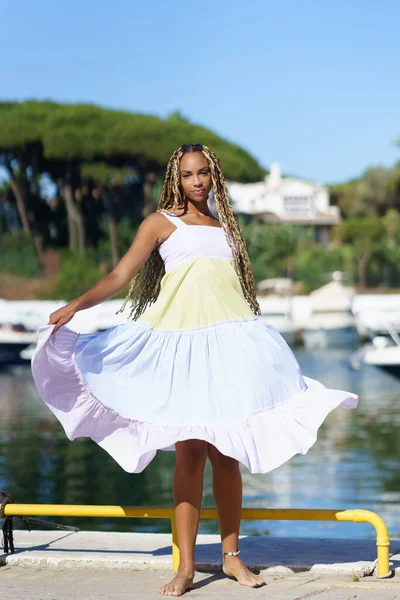 Schwarze Frau läuft in einem schönen Sommerkleid an einem Hafen entlang. — Stockfoto