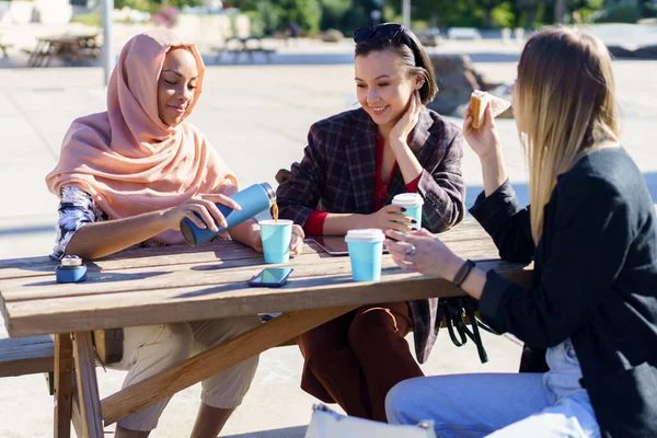 Positieve diverse vrouwen met koffiepauze aan tafel in het park — Stockfoto