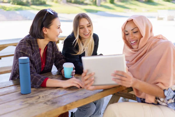 Alegre diversas senhoras compartilhando tablet durante coffee break no café — Fotografia de Stock