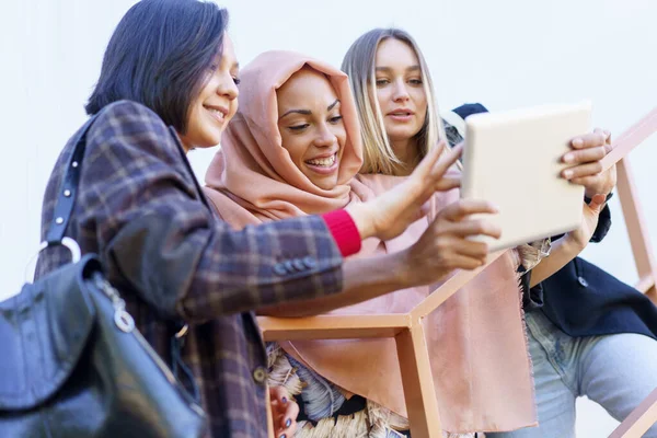 Sorrindo jovens senhoras diversas usando tablet nas escadas — Fotografia de Stock