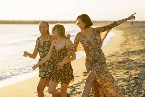 Riendo diversas mujeres disfrutando de la puesta de sol en la playa — Foto de Stock