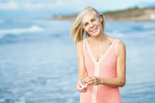 stock image Mature woman on shore of a beach. Elderly female enjoying her retirement at a seaside retreat.