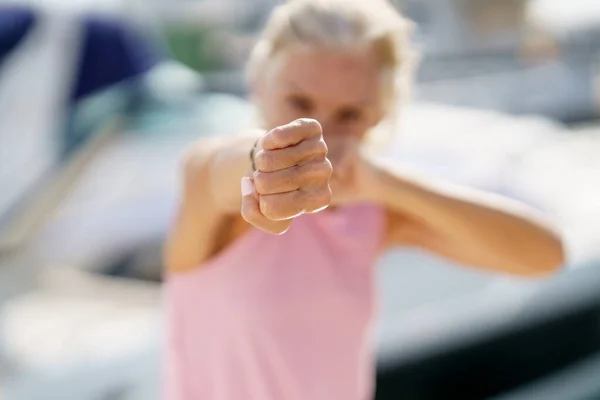 Starší ženy boxují venku ve stínu. Senior žena dělá sport v pobřežním přístavu — Stock fotografie