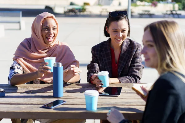 Feliz diversas mujeres tomando un café y charlando al aire libre — Foto de Stock