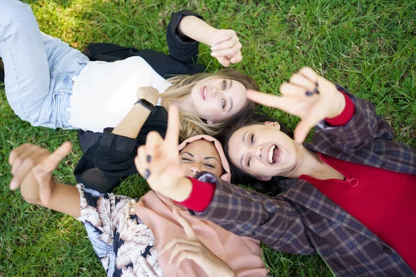 잔디 위에 누워 카메라를 만지고 있는 쾌활 한 숙녀들 — 스톡 사진