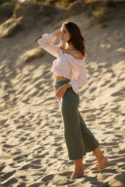 Genç ve güzel bir kadın kumsalda duruyor.