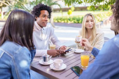 Çok ırklı bir arkadaş grubu açık hava barında birlikte içki içiyorlar..