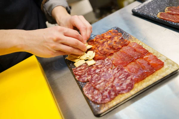 Chef irreconhecível preparando um prato de bandeja de carnes curadas ibéricas. — Fotografia de Stock