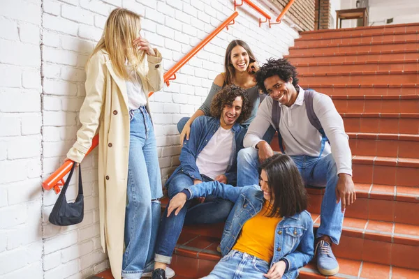 Grupo de estudiantes con variedad étnica, sentados en algunos escalones de la calle divirtiéndose juntos. — Foto de Stock