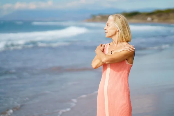 Mature woman on shore of a beach. Elderly female enjoying her retirement at a seaside retreat. — Stock Photo, Image